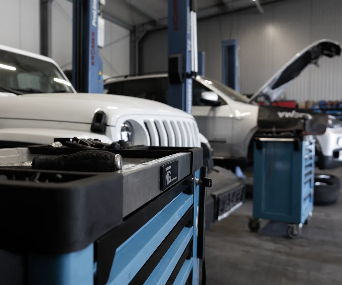 Eine KFZ-Werkstatt mit mehreren Autos im Hintergrund, Werkzeuge im Vordergrund