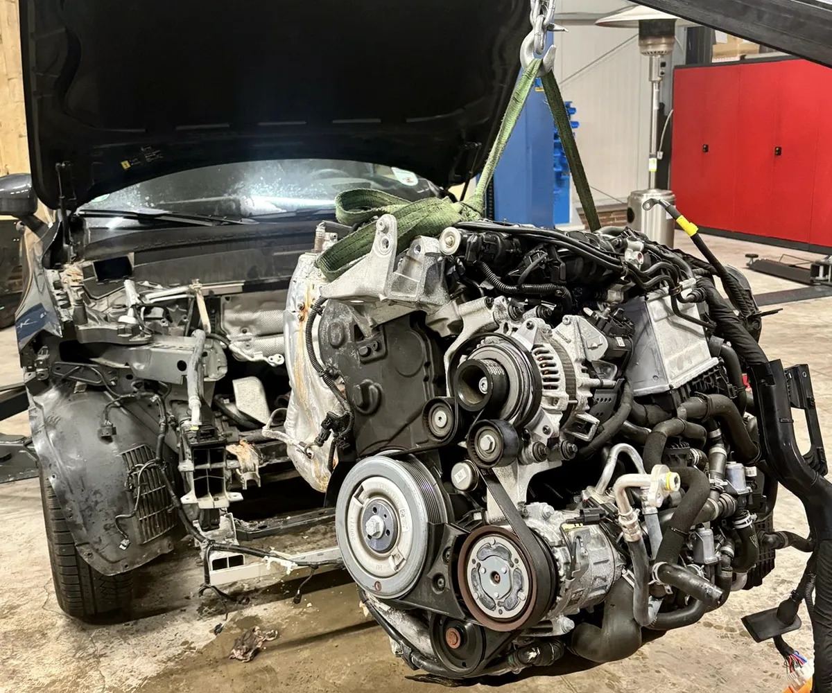 Ein Motorblock hängend über einem leeren Motorraum